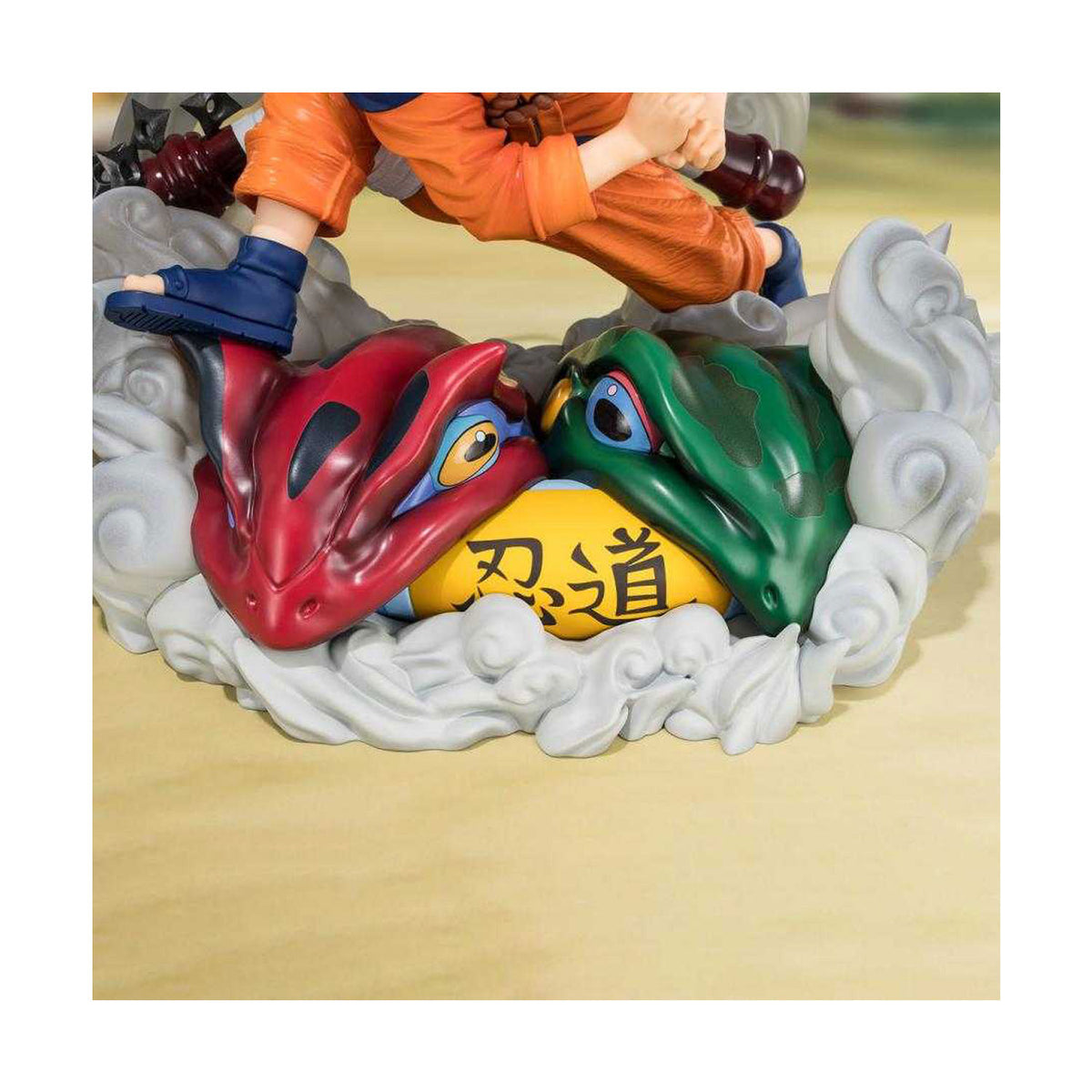 Die Naruto Uzumaki Figur von FiguartsZero von Bandai, mit einem roten und grünen Frosch mit Schriftrolle im Mund.